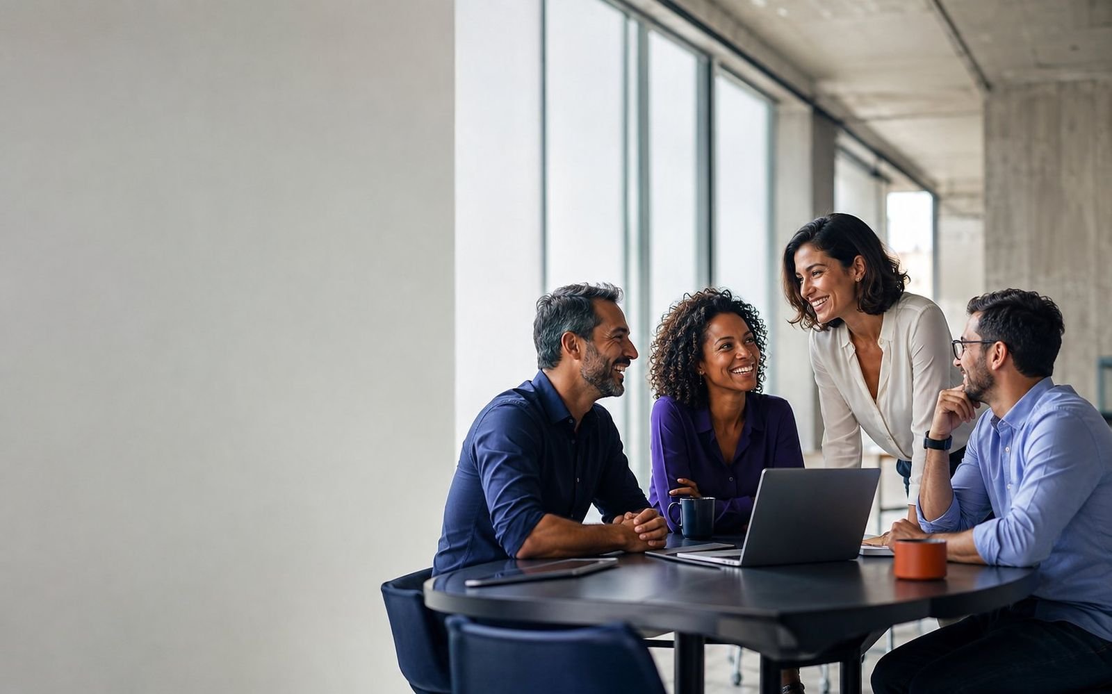 Equipe comercial reunida em torno de um notebook, sorrindo durante uma reunião de parceria